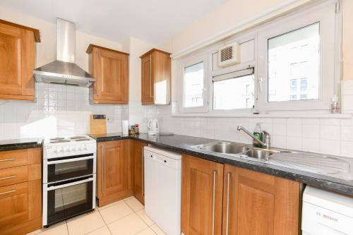 a kitchen with wooden cabinets and a sink at Flat near Angel St City University & Tube- MAC 1 in London