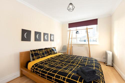 1 dormitorio con 1 cama de color amarillo y negro en Easy living near Angel and City University, en Londres