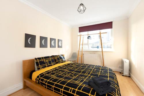 a bedroom with a bed with a yellow and black at Flat near Angel St City University & Tube- MAC 1 in London