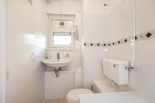a white bathroom with a toilet and a sink at Flat near Angel St City University & Tube- MAC 1 in London