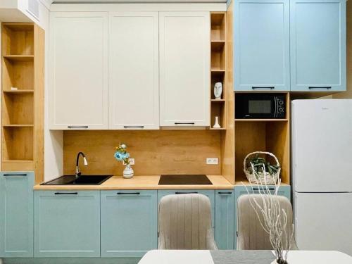 a kitchen with blue cabinets and a white refrigerator at ЖК Homeland EXPO 2 комн in Taldykolʼ