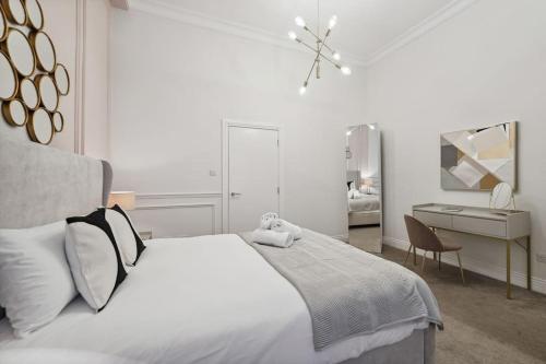 (G5) Grand 1 bed Blythswood Apartment في غلاسكو: غرفة نوم بيضاء مع سرير كبير ومكتب
