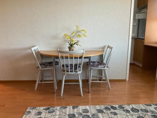 a table with three chairs and a potted plant on it at Studiohuoneisto Lohja keskusta in Lohja