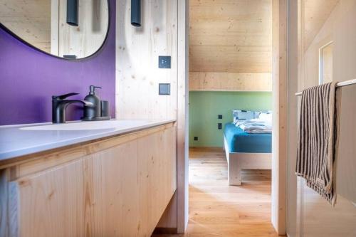 a bathroom with a sink and a mirror and a bed at The Swiss Bijou / Alpine Retreat in Stans