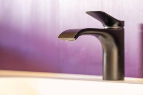 a black faucet on a bathroom sink at The Swiss Bijou / Alpine Retreat in Stans
