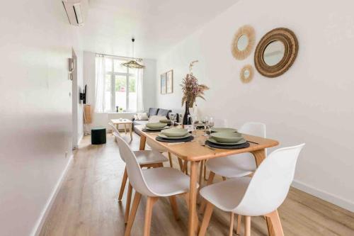 uma sala de jantar com uma mesa e cadeiras brancas em Appartement RDC Mairie de Marcq em Marcq-en-Baroeul