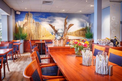 een restaurant met een tafel en stoelen en een muurschildering bij Hotel Astoria in Noordwijk aan Zee
