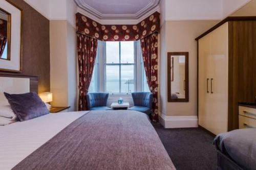 um quarto de hotel com uma cama grande e uma janela em Lauriston & Lawton Court Hotel em Llandudno