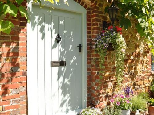 a white door on a brick house with flowers at Mill Barn in Chailey