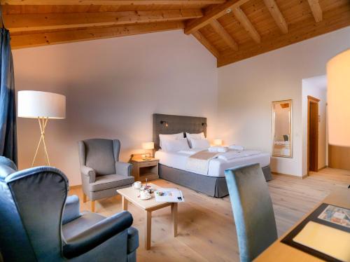 a hotel room with a bed and two chairs at Dolomitengolf Hotel & Spa in Lavant