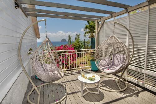 een veranda met 2 stoelen en een tafel op een balkon bij Cœur de Diams in Le Diamant