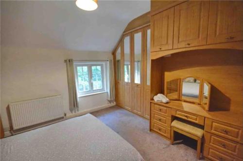 Schlafzimmer mit einem Bett, einem Schreibtisch und einem Fenster in der Unterkunft Dale Cottage 18th Century Country Cottage, 111 Barnston road in Heswall