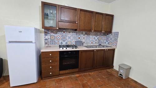 a kitchen with wooden cabinets and a white refrigerator at Appartamento La Locanda Del Castello in San Panfilo dʼOcre