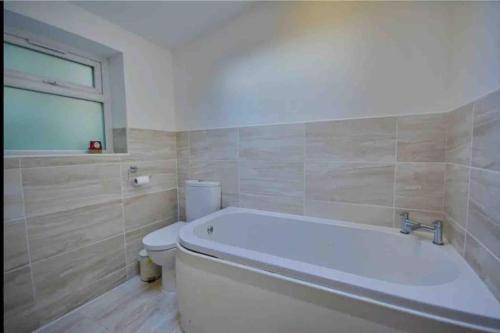 a bathroom with a white tub and a toilet at Dale Cottage 18th Century Country Cottage, 111 Barnston road in Heswall