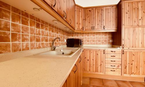 een keuken met houten kasten en een wastafel bij Casa de Las Flores in Cruce de Arinaga