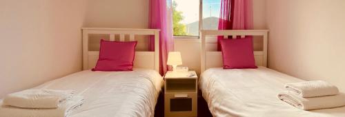 2 camas en una habitación pequeña con almohadas rosas en Casa de Las Flores, en Cruce de Arinaga
