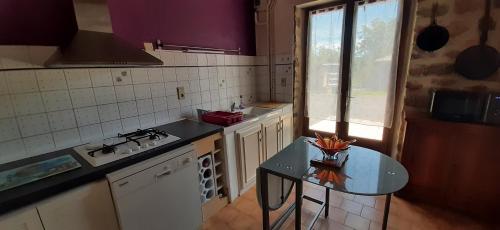 une cuisine avec une table et un comptoir dans l'établissement Les Sabots D'Angélina, à Saint-Bonnet-lʼEnfantier