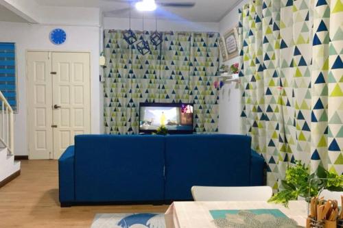 ein Wohnzimmer mit einem blauen Sofa und einem TV in der Unterkunft Lily's HomeStay in Kulim