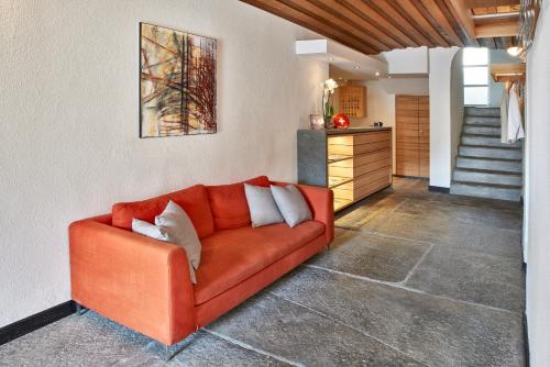ein orangefarbenes Sofa im Wohnzimmer mit einer Treppe in der Unterkunft Hotel Bellevue in San Bernardino