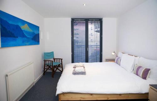 a bedroom with a large white bed and a chair at JOIVY Inviting Flat with Parking in Canonmills in Edinburgh