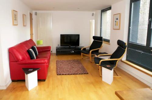 a living room with a red couch and chairs at JOIVY Inviting Flat with Parking in Canonmills in Edinburgh