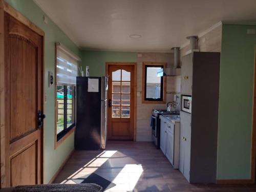 a kitchen with green walls and a black refrigerator at Turismo El Embrujo in Coihaique