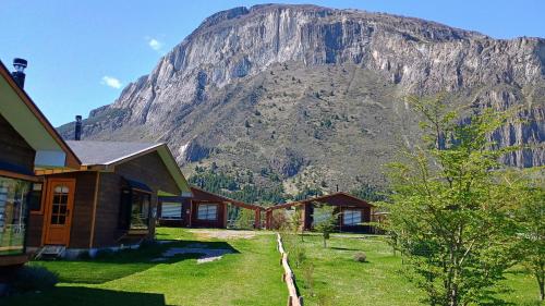 una montaña en la distancia con casas delante en Turismo El Embrujo, en Coyhaique