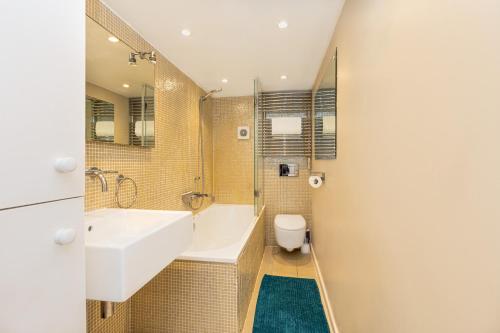 a bathroom with a tub and a sink and a toilet at Amazing 3-Storey 2BR House, Patio, 5 min Limehouse in London