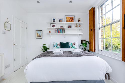 a bedroom with a large bed with white walls at Amazing 3-Storey 2BR House, Patio, 5 min Limehouse in London