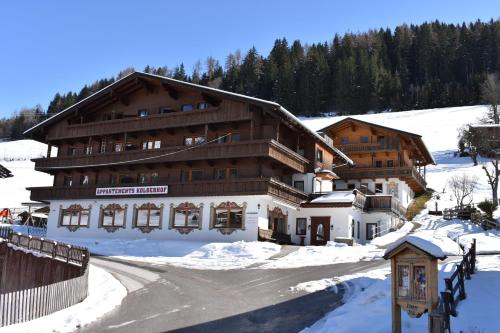 a large building in the snow with a road in front at Appartements Kolberhof in Alpbach