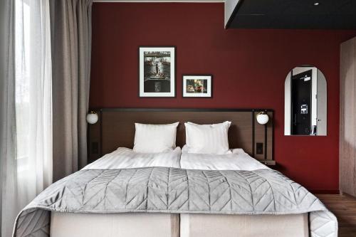 a bedroom with a large bed with red walls at Best Western Plus Hotel Kungens Kurva in Stockholm