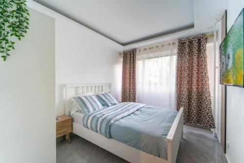 una camera bianca con un letto e una finestra di Sisyphe - Appt à 30 minutes de Disneyland Paris a Chennevières-sur-Marne