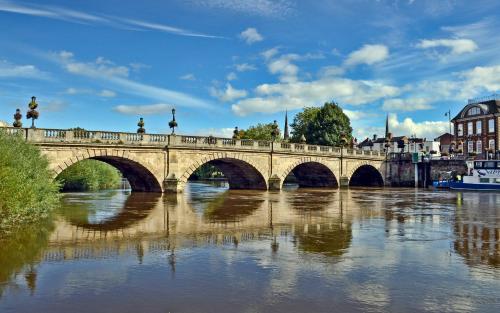 eine Brücke über einen Fluss mit Reflexionen im Wasser in der Unterkunft The Shire Residence in Shrewsbury