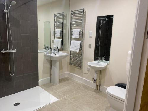 uma casa de banho com 2 lavatórios, um chuveiro e um WC. em The Shire Residence em Shrewsbury