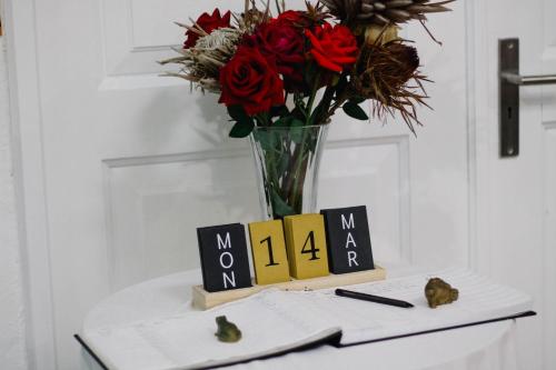 a table with a vase of flowers and a vase of roses at La Dolce Vita Umhlanga Guesthouse in Durban