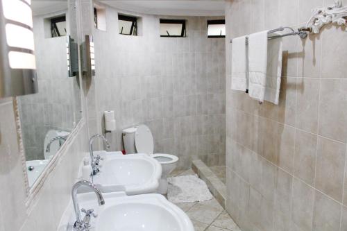 a bathroom with two sinks and a toilet at La Dolce Vita Umhlanga Guesthouse in Durban