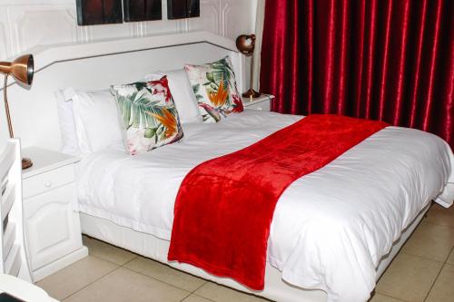 a bedroom with a white bed with a red blanket at La Dolce Vita Umhlanga Guesthouse in Durban