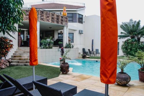 a villa with a swimming pool in front of a house at La Dolce Vita Umhlanga Guesthouse in Durban