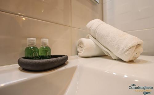 La salle de bains est pourvue d'une baignoire avec une serviette et 2 bouteilles. dans l'établissement COUTELIERS - Hypercentre Carmes - Métro à 4min, à Toulouse