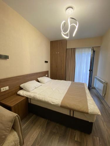 Un dormitorio con una cama grande y una lámpara de araña. en Crystal resort b209, en Bakuriani