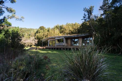 a house in the middle of a field with trees at Casas Martín Pescador, Lago Huillinco, Chiloe in Chonchi