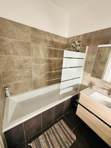une salle de bain avec une baignoire blanche et un lavabo dans l'établissement Appartement Lumineux et Spacieux 2 Chambres avec Parking Gratuit dans la Rue, à Perpignan