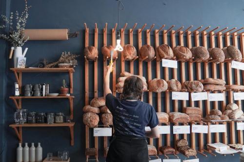 a woman is looking at a display of bread at The Dial House in Reepham