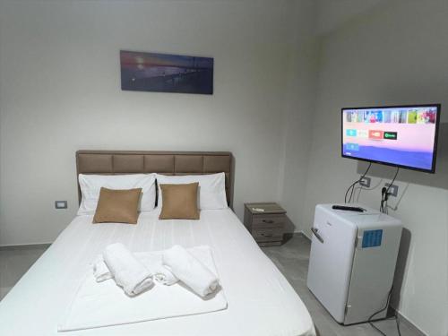 Schlafzimmer mit einem weißen Bett und einem Flachbild-TV in der Unterkunft Shell and Bells in Vlorë