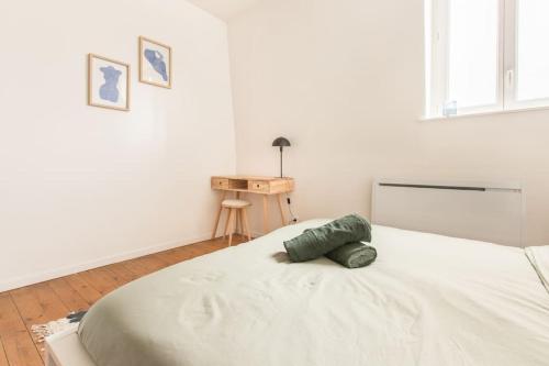 a white bedroom with a bed with a green pillow on it at Appartement 3 Mairie de Marcq en Baroeul in Marcq-en-Baroeul