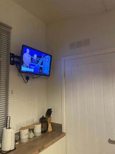 a television hanging on a wall in a room at Pwllglas Bach - Spacious Cabin in Machynlleth