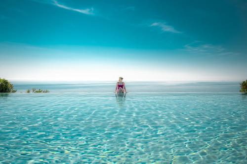 Une femme debout dans l'eau dans l'océan dans l'établissement Le Capase Resort Salento, à Santa Cesarea Terme