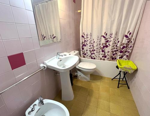 a bathroom with a sink and a toilet and a shower curtain at Apartamento con vistas al mar y piscina in Pineda de Mar