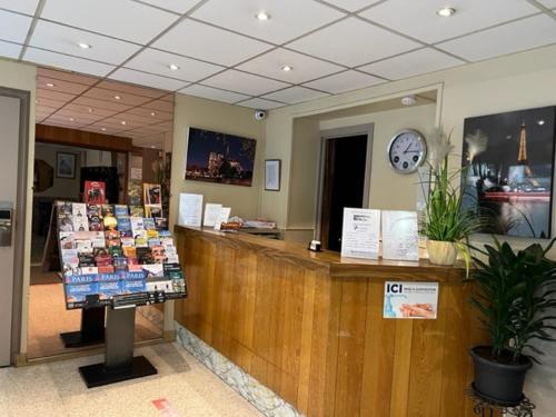 un magasin avec un comptoir avec une horloge sur le mur dans l'établissement Hôtel Jarry Confort, à Paris