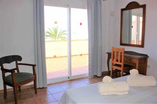 コラレホにあるCASA MARTA duplex con piscina privada en Corralejoのベッド、テーブル、鏡が備わる客室です。